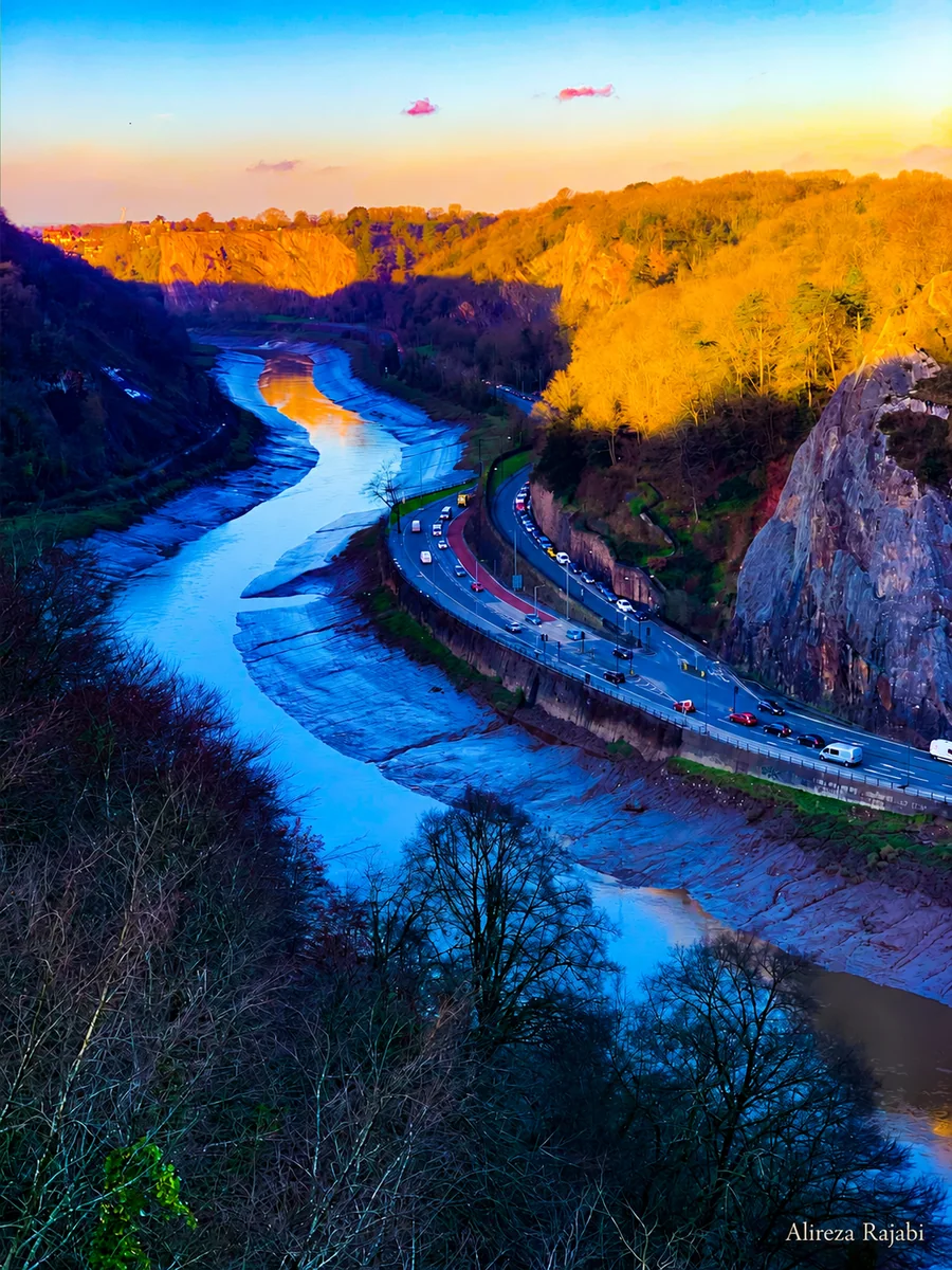 A road following a river through a sunlit gorge