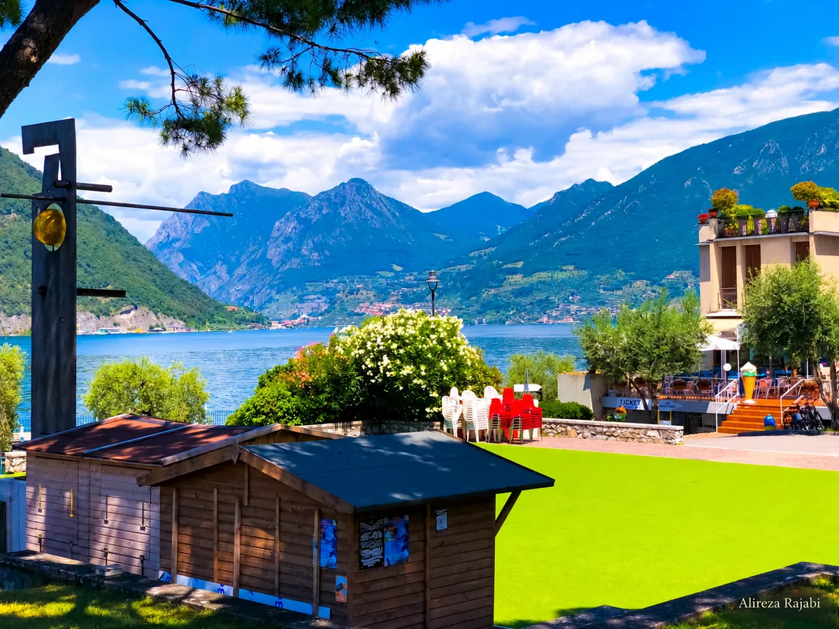 A lakeside view with mountains and a green lawn